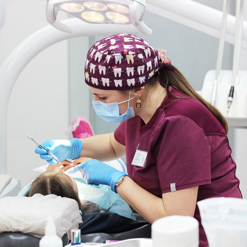 Врач-ортодонт осматривает прикус маленький пациентки